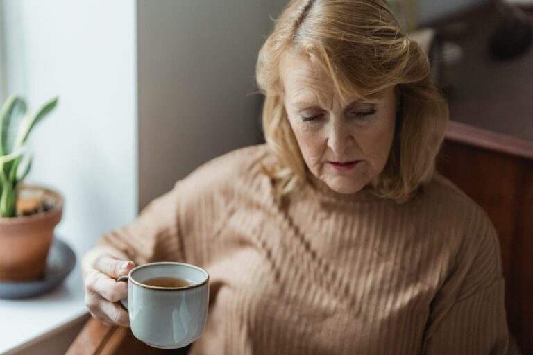 Elderly woman unwinding with a hot cup of tea at home, embodying serenity and calm.