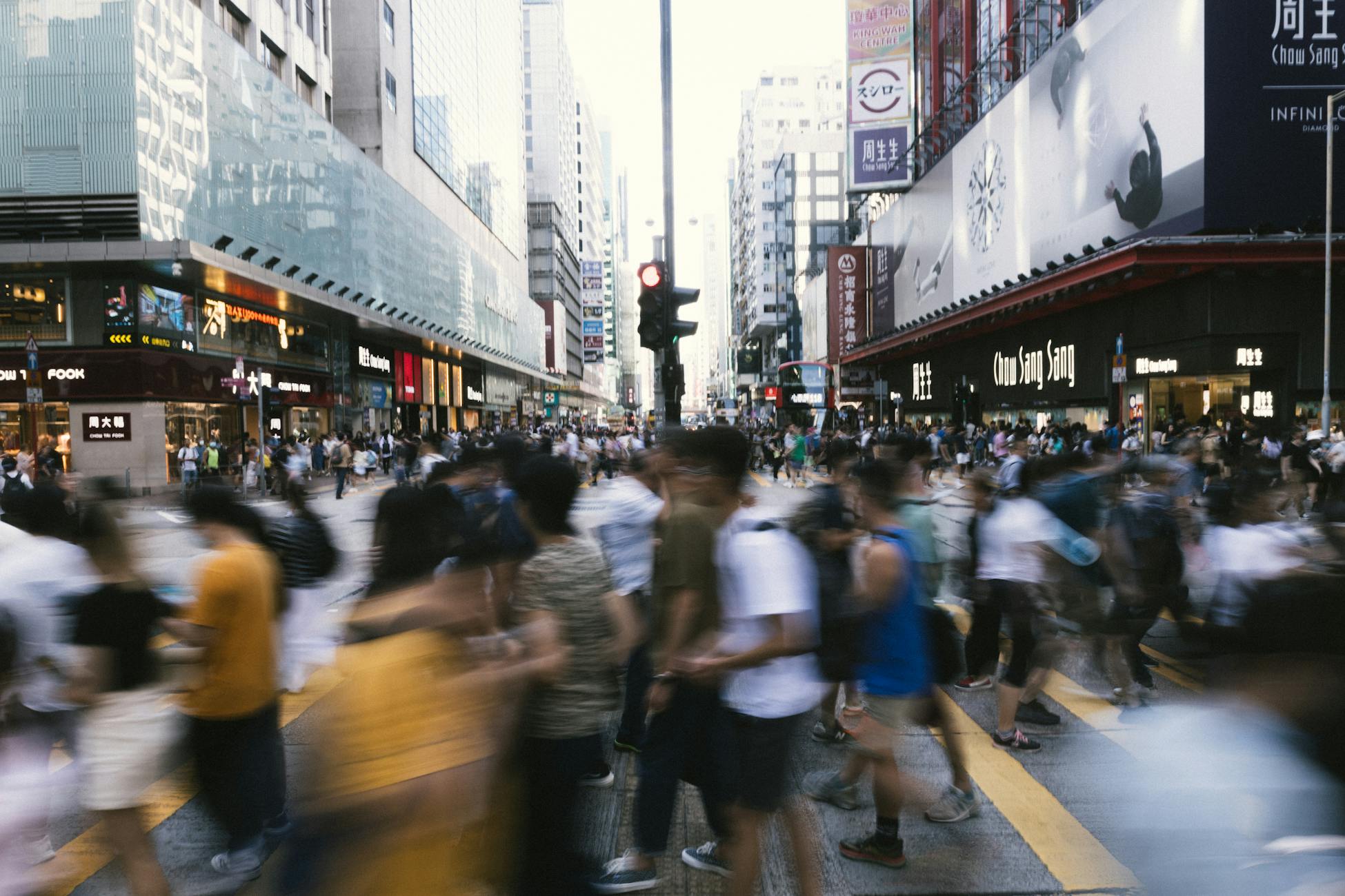 Dynamic scene of people crossing a bustling street in downtown Hong Kong, showcasing urban life.