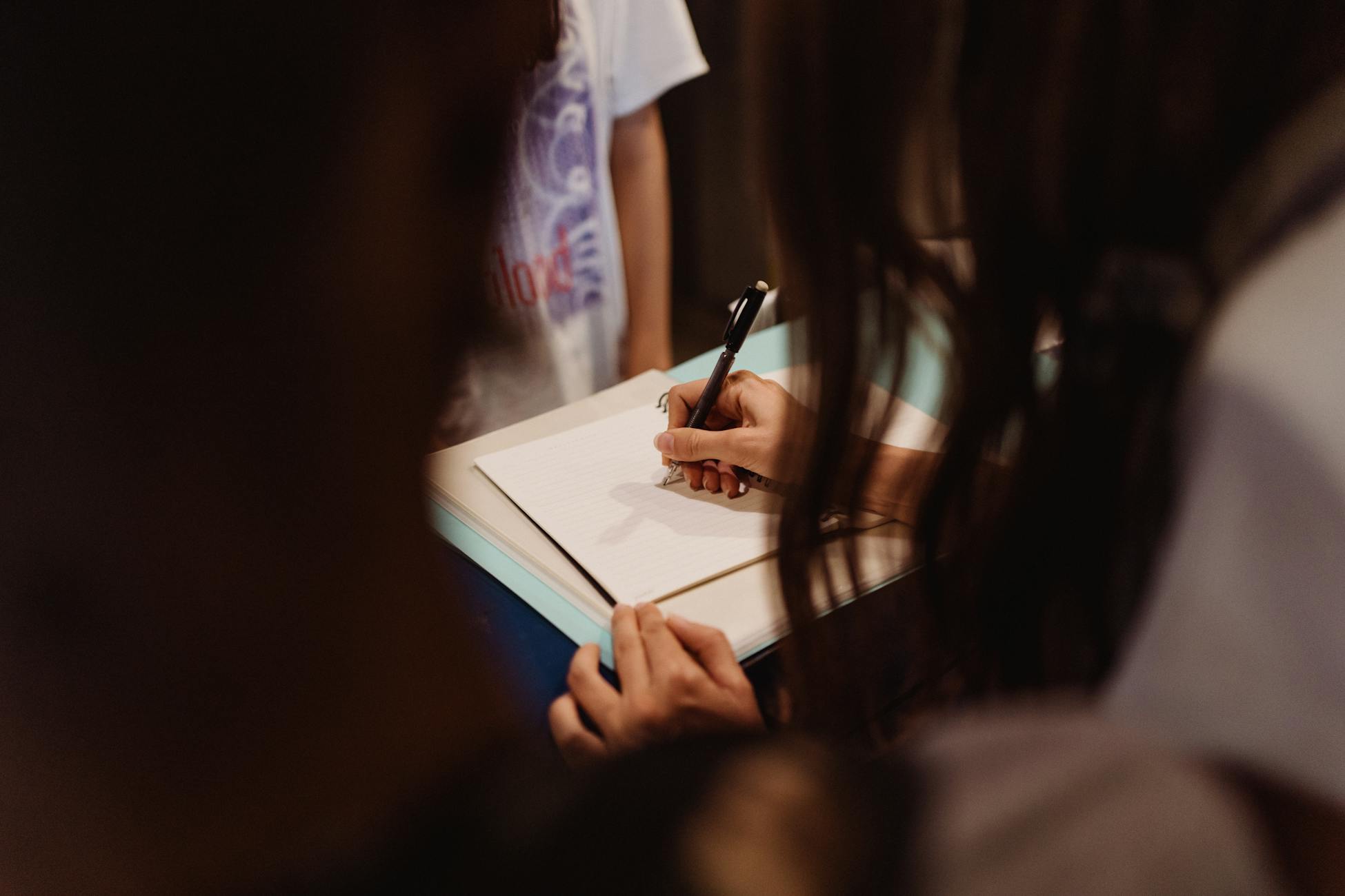 A woman writing in a notebook with a pen, focused and engaged.