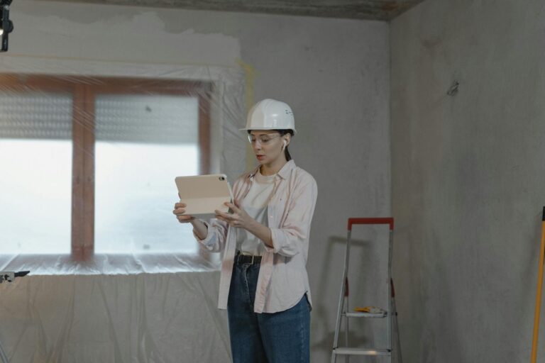Woman in hard hat using tablet for construction project in unfinished interior.