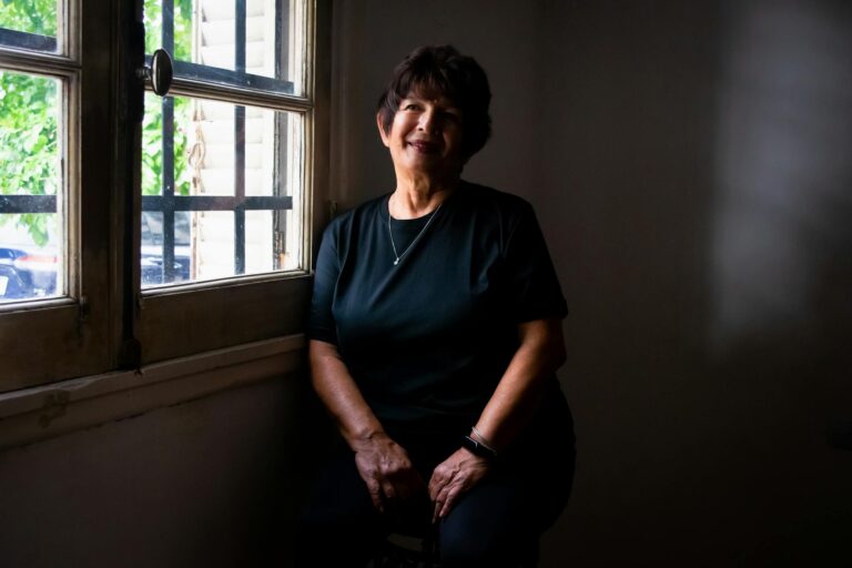 Graceful woman sitting by the window with gentle light indoors, exuding warmth.