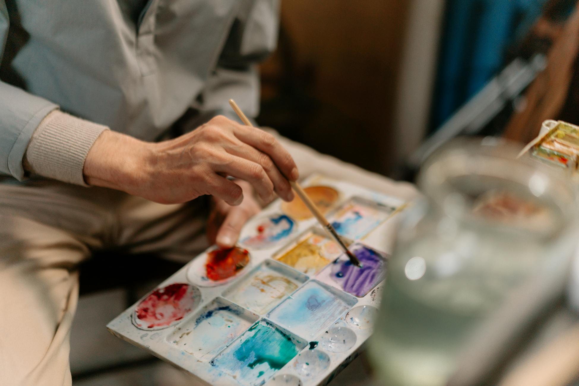 Close-up of an artist blending colors on a palette in a studio setting.