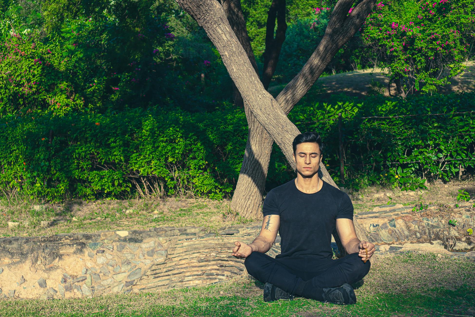 Man meditating peacefully in a lush Jaipur garden, embracing wellness and relaxation.